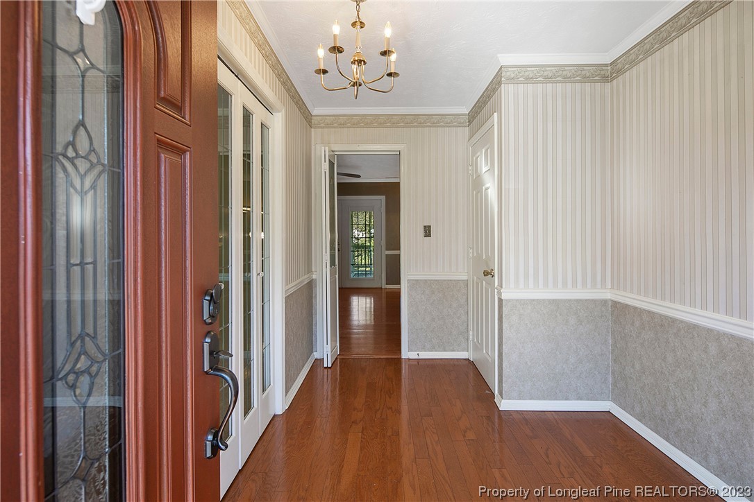 6875 Baystone Road Fayetteville, NC 28314 - Photo 5 of 50 a view of a hallway with wooden floor and a chandelier