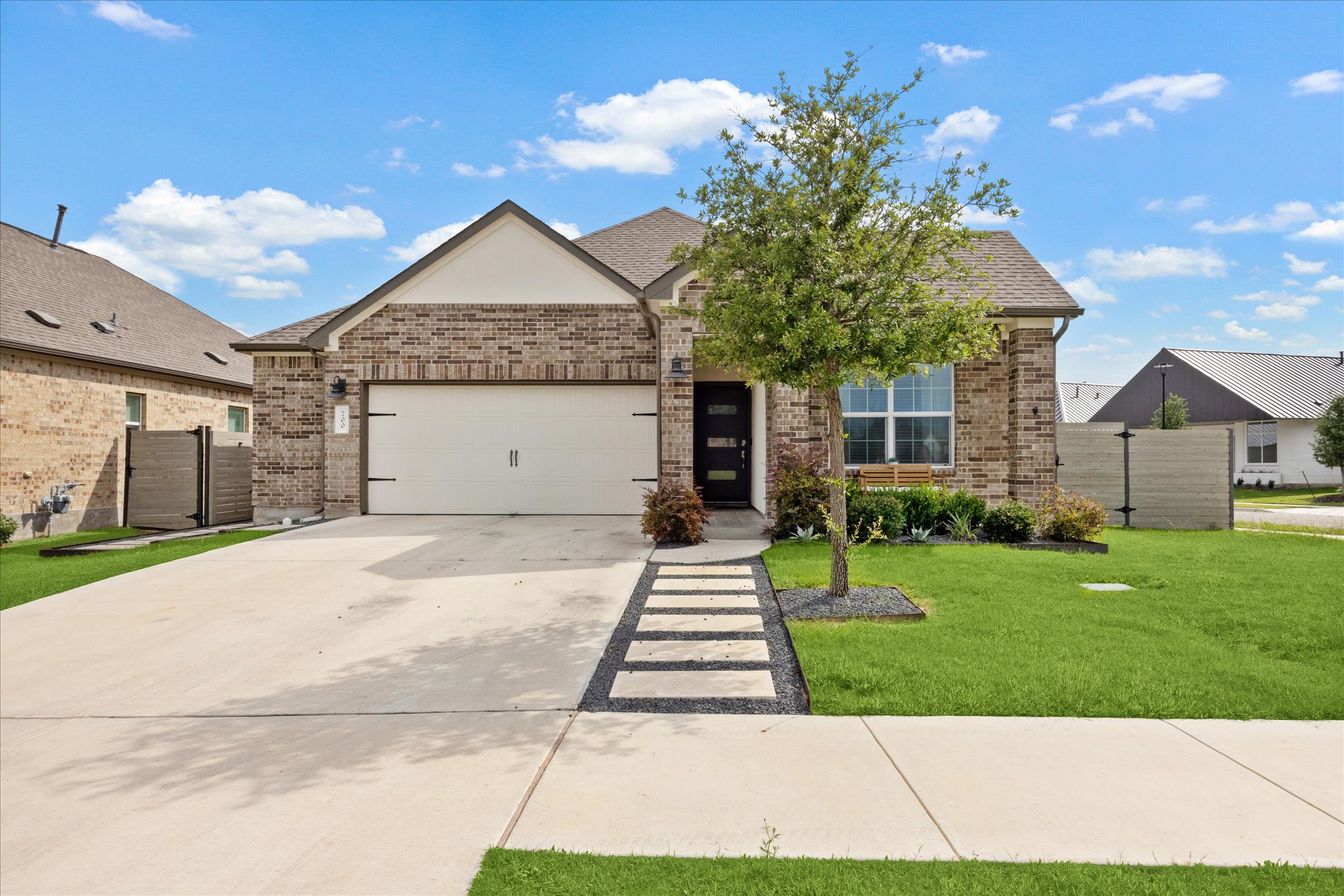 View of front facade with a garage, concrete driveway, brick siding, and a shingled roof