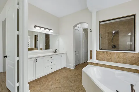 a spacious bathroom with a tub sink and mirror