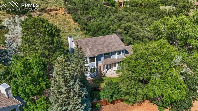 an aerial view of a house with yard outdoor space and trees all around