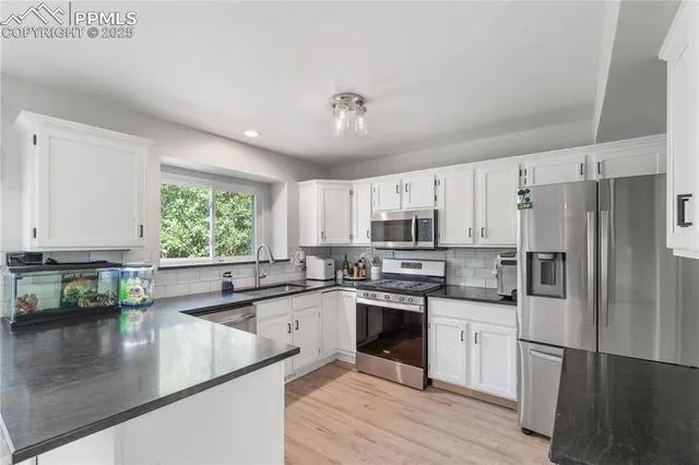 a kitchen with stainless steel appliances granite countertop a sink window and cabinets