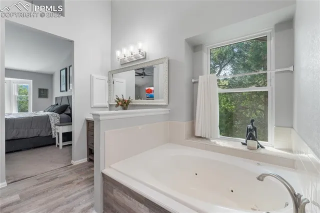 a en suite spacious bathroom with a tub double vanity and window