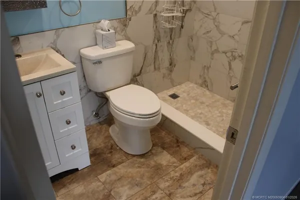 a white toilet sitting next to a bathroom sink and vanity