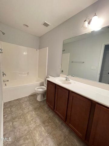 a spacious bathroom with a double vanity sink toilet mirror and bathtub