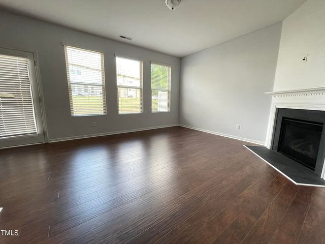 an empty room with wooden floor and fireplace