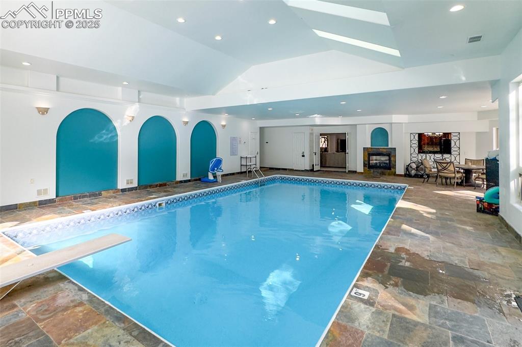 17502 Abert Ridge View Colorado Springs, CO 80908 - Photo 39 of 50 Indoor pool featuring a skylight, arched walkways, and a diving board