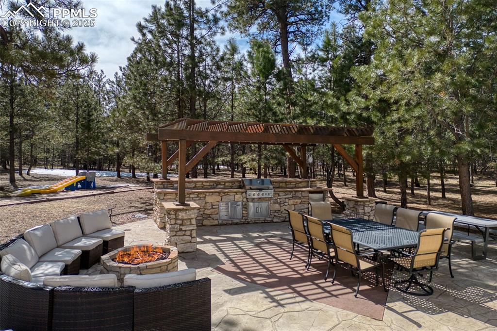 17502 Abert Ridge View Colorado Springs, CO 80908 - Photo 42 of 50 View of patio with area for grilling, an outdoor kitchen, an outdoor living space with a fire pit, and outdoor dining space