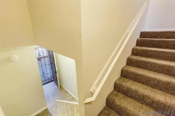 a view of staircase with wooden floor and white walls