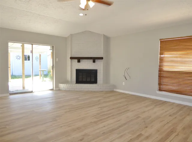 a view of an empty room with a window and wooden floor