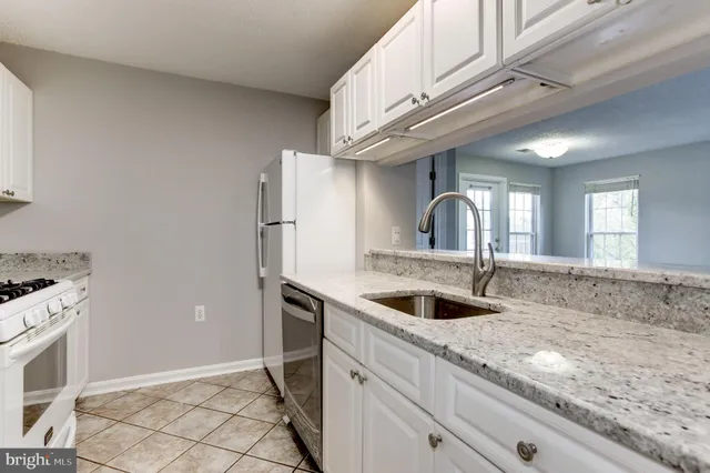 a kitchen with granite countertop a sink and a refrigerator