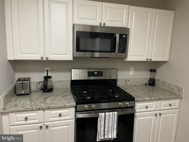 a kitchen with granite countertop white cabinets and a stove top oven