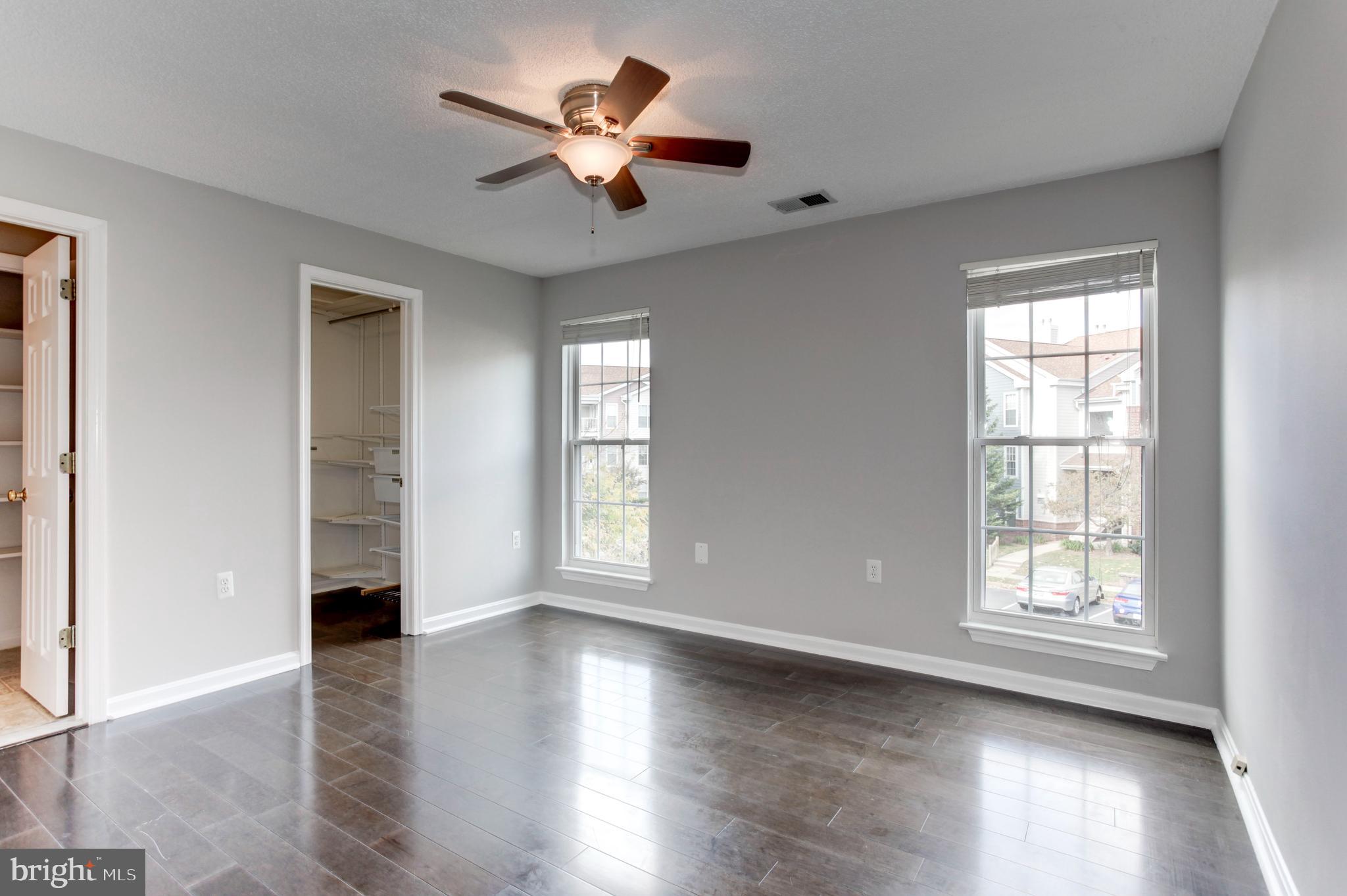 21012 Timber Ridge Terrace, Unit 201 Ashburn, VA 20147 - Photo 31 of 37 an empty room with wooden floor chandelier fan and windows