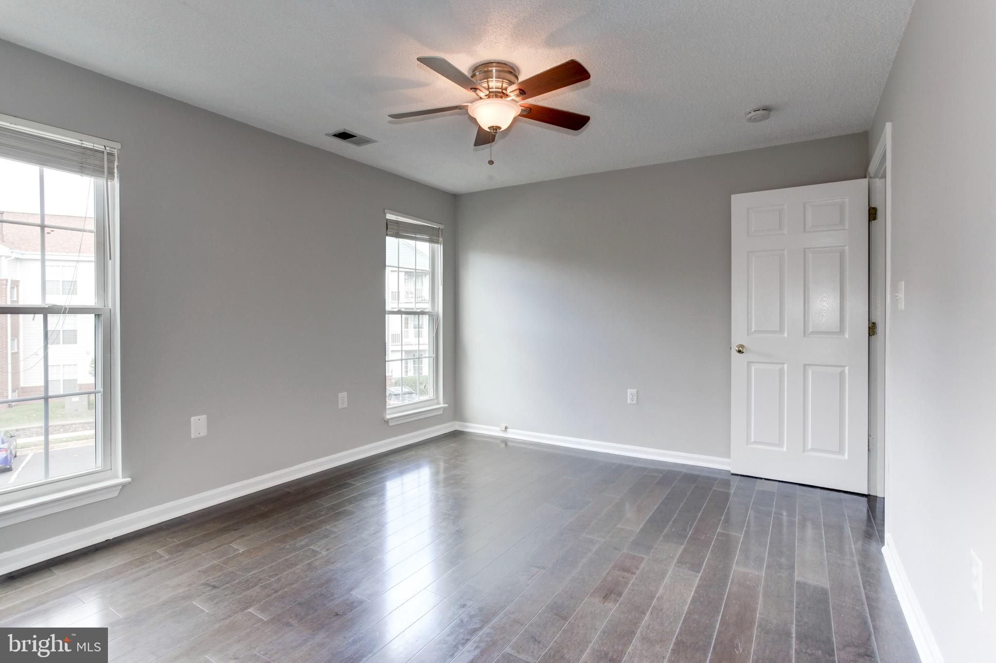 21012 Timber Ridge Terrace, Unit 201 Ashburn, VA 20147 - Photo 32 of 37 an empty room with wooden floor and windows