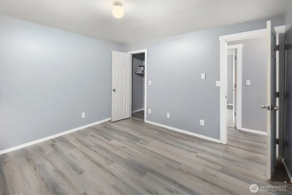 a view of an empty room with wooden floor and a bathroom