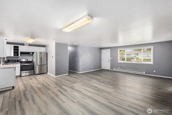 a view of an empty room with window and wooden floor
