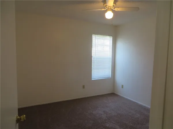 an empty room with a chandelier fan and a window