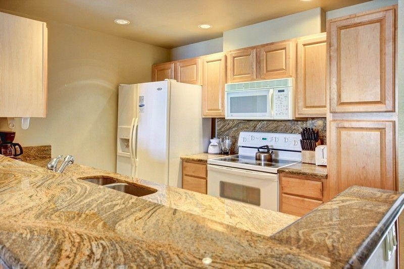 3445 Lower Honoapiilani Road, Unit 255 Lahaina, HI 96761 - Photo 8 of 35 a kitchen with stainless steel appliances granite countertop a refrigerator sink and wooden cabinets
