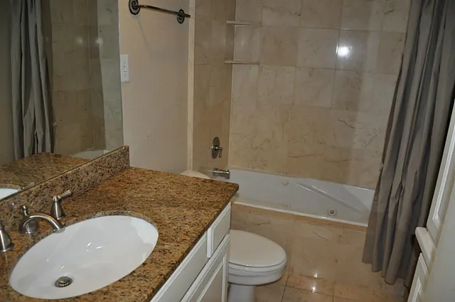 a bathroom with a granite countertop sink toilet and shower