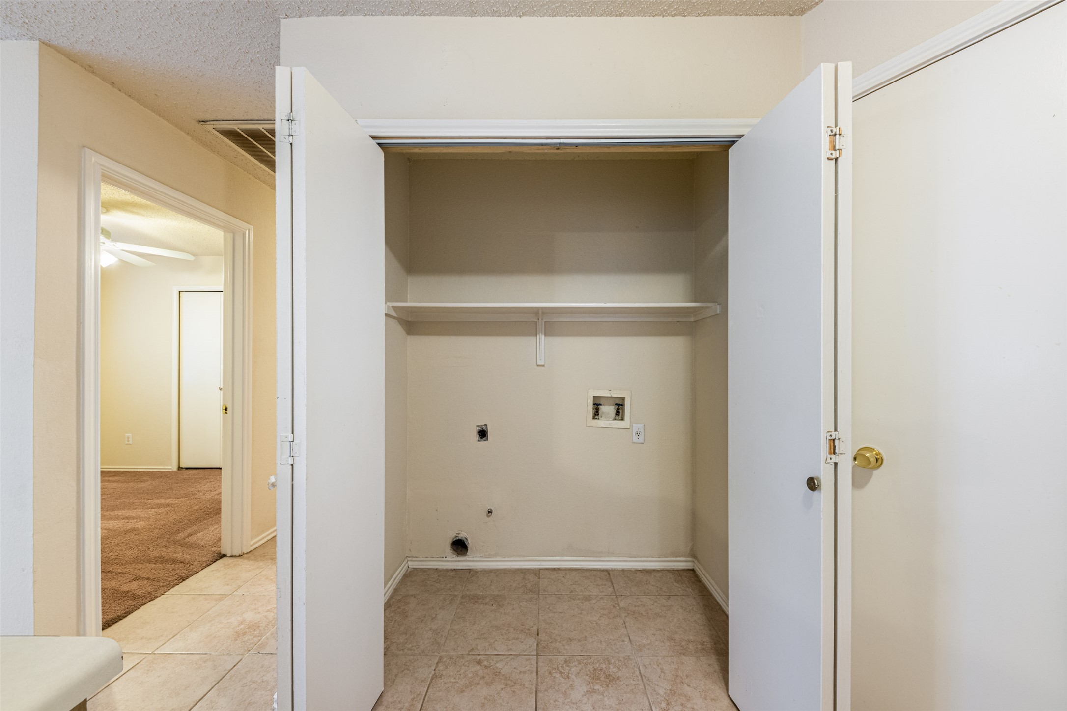 7216 Aldea Drive, Unit A Austin, TX 78745 - Photo 13 of 25 Dedicated utility closet with tile flooring, wall-mounted shelving, and laundry hookups