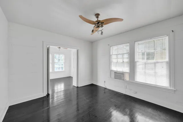 a view of empty room with wooden floor and fan