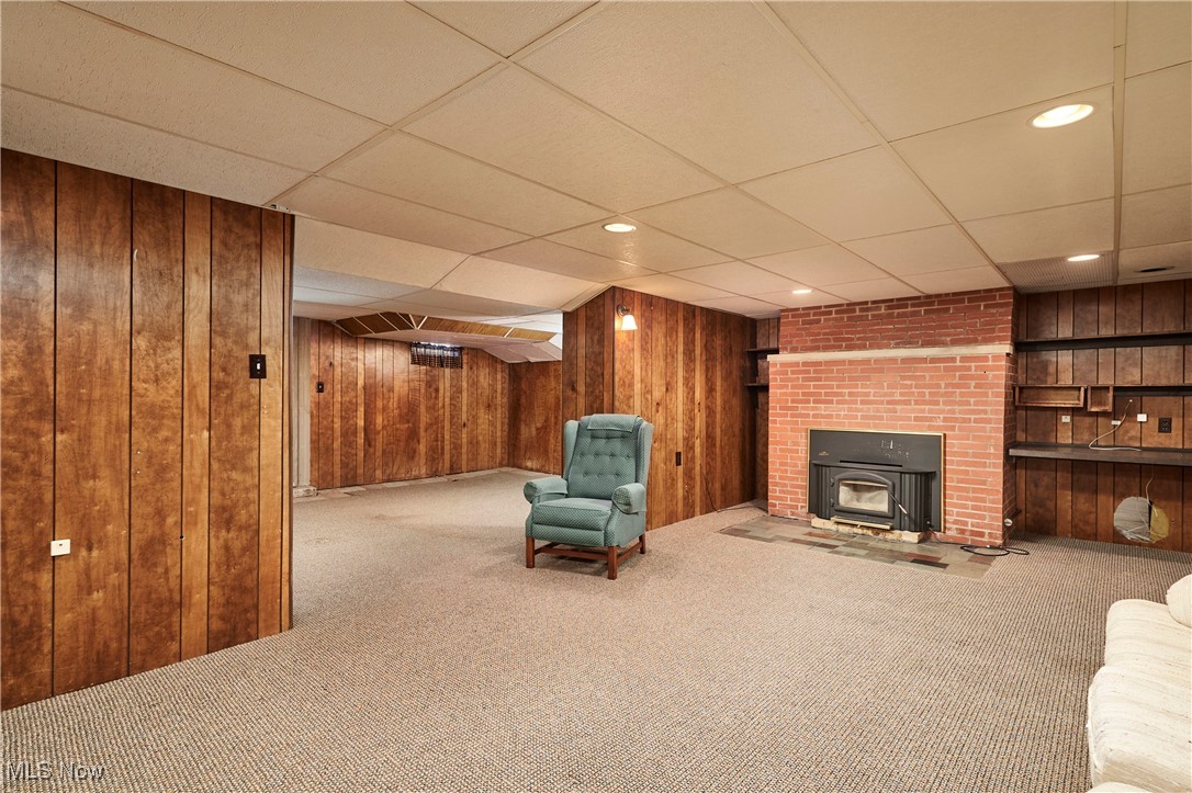 650 Rothrock Circle Akron, OH 44321 - Photo 30 of 31 Unfurnished lbasement iving area featuring carpet floors, wooden walls, a paneled ceiling, and a wood stove