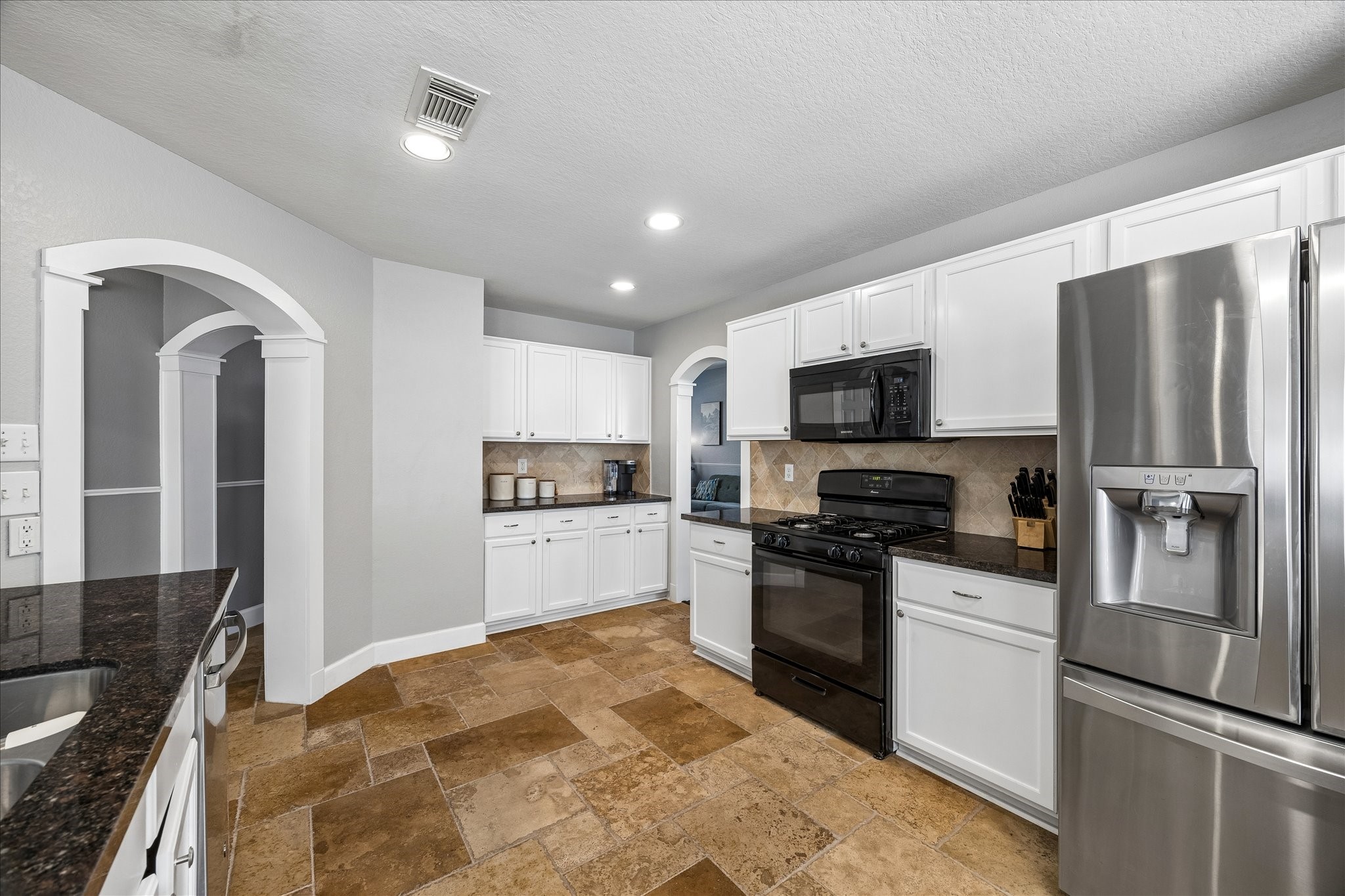 23234 Grand Rapids Lane Spring, TX 77373 - Photo 11 of 30 Well-designed kitchen offers ample white cabinetry, granite counters, and stainless appliances with easy access to adjoining living spaces.