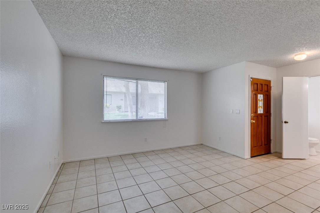2681 Ruthe Duarte Avenue Las Vegas, NV 89121 - Photo 8 of 43 Empty room featuring a textured ceiling, baseboards, and light tile patterned flooring