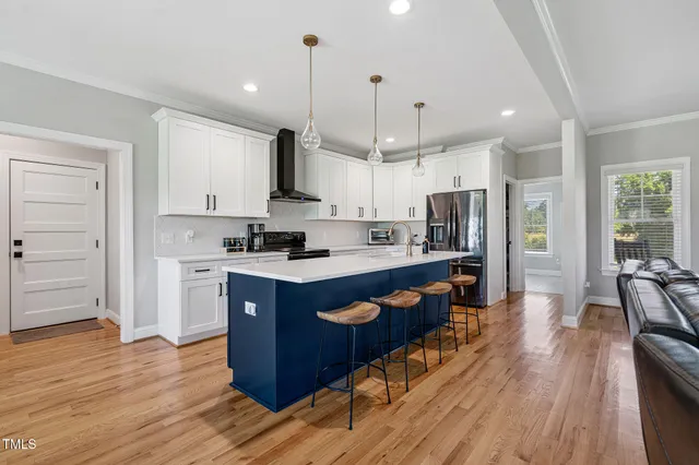 a kitchen with stainless steel appliances kitchen island granite countertop a refrigerator a stove a sink and a wooden floors