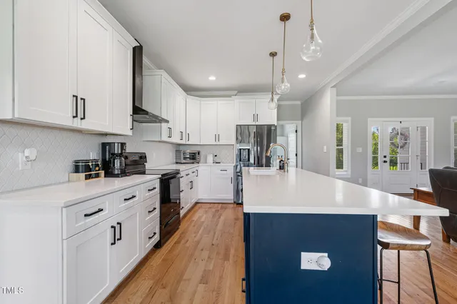 a large white kitchen with lots of counter space wooden floor and stainless steel appliances