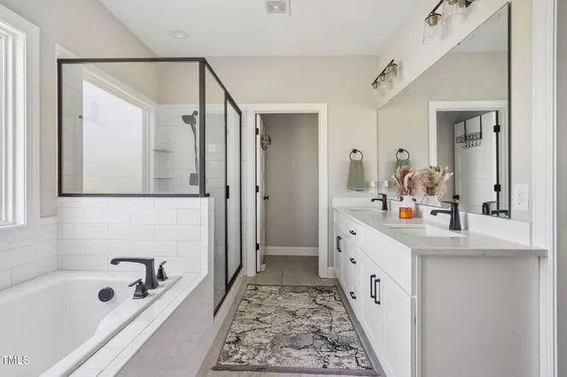 a bathroom with a double vanity sink a mirror a bathtub and shower