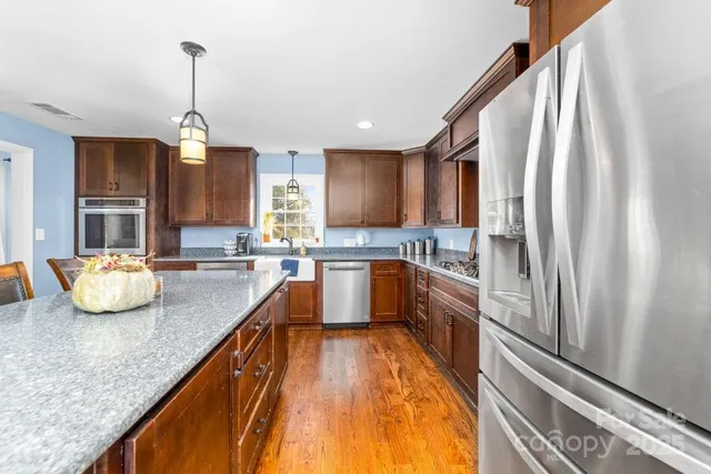 a kitchen with stainless steel appliances granite countertop a sink refrigerator and cabinets