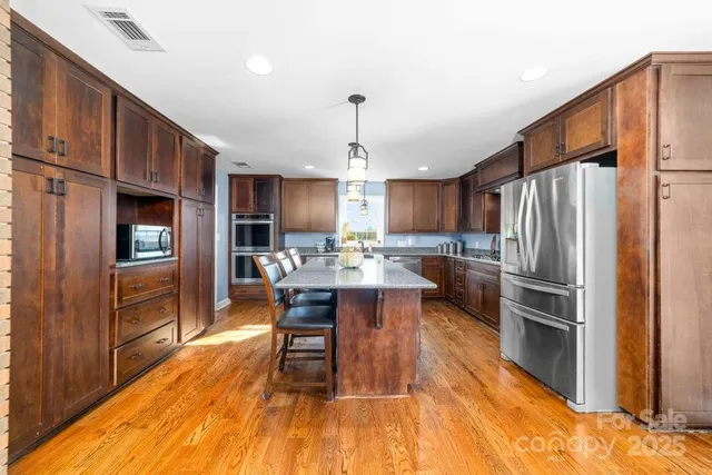 a kitchen with stainless steel appliances a dining table chairs stove refrigerator and cabinets
