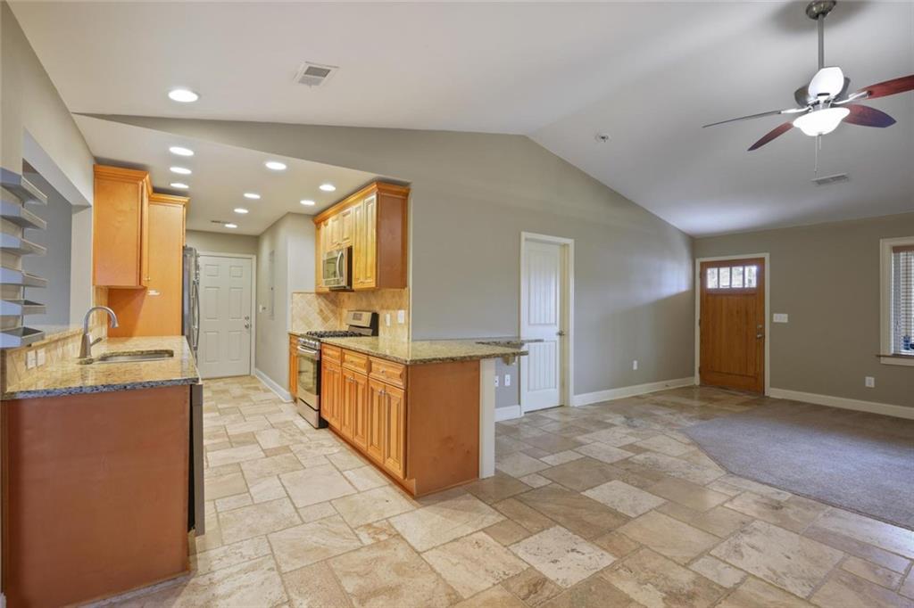 3851 Trickum Road Marietta, GA 30066 - Photo 9 of 27 a large kitchen with stainless steel appliances a large counter top a stove a chimney a sink and dishwasher