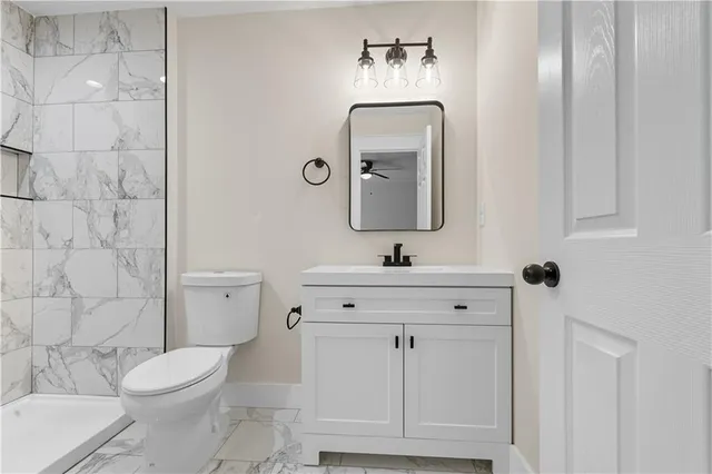 a bathroom with a toilet a sink a mirror and vanity