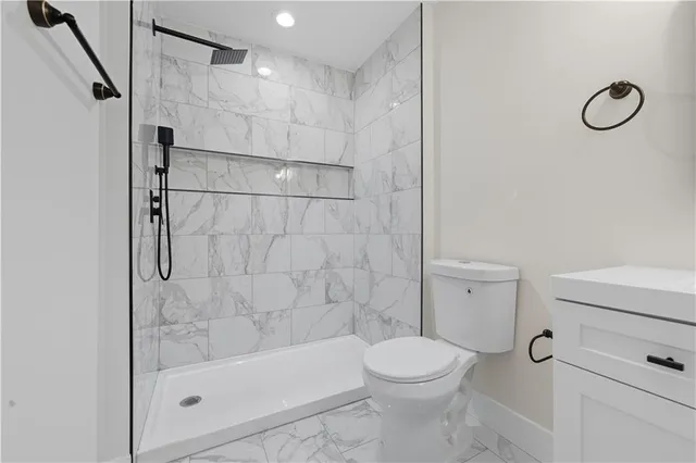 a bathroom with a granite countertop bathtub shower sink vanity and toilet