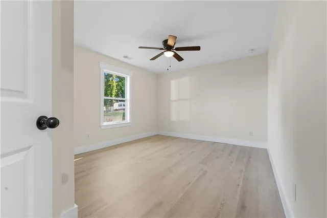 an empty room with windows and fan