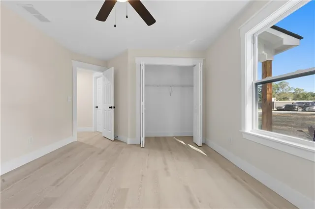 an empty room with chandelier fan and windows