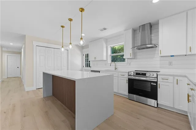 a kitchen with stainless steel appliances white cabinets a sink and a stove