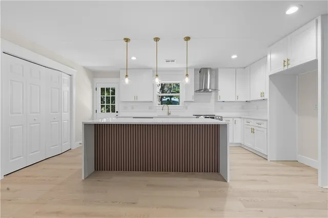a kitchen with kitchen island granite countertop a sink cabinets and stainless steel appliances