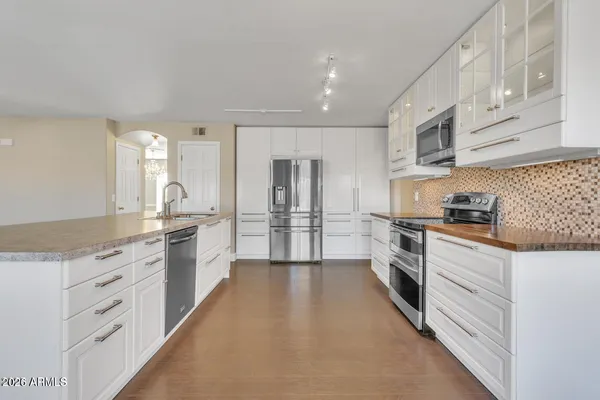 a large kitchen with granite countertop a large counter top space a sink stainless steel appliances and cabinets