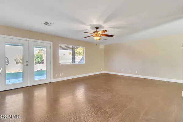 an empty room with windows and chandelier fan