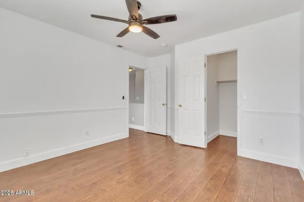 an empty room with wooden floor ceiling fan and windows