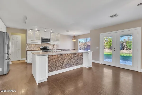 a kitchen with stainless steel appliances kitchen island granite countertop a refrigerator oven a sink with wooden cabinets and wooden floor