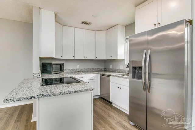 a kitchen with stainless steel appliances granite countertop a refrigerator a stove and a sink