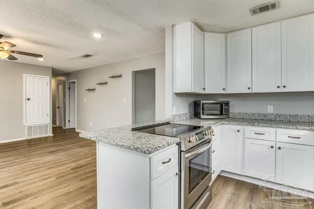 a kitchen with granite countertop white cabinets and white appliances