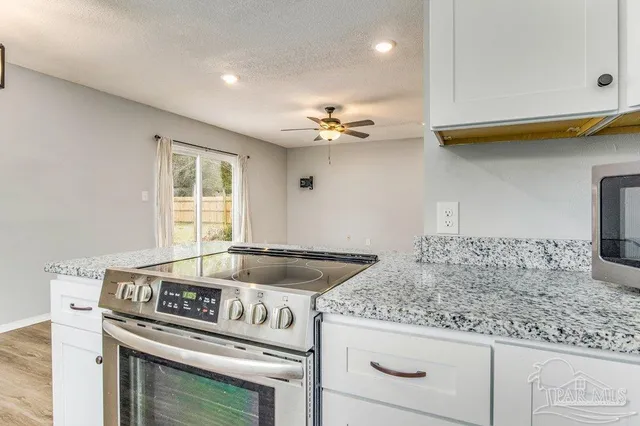 a kitchen with granite countertop a sink a stove and cabinets