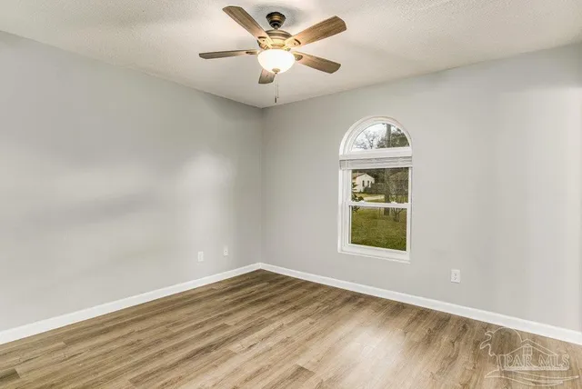 an empty room with a window and ceiling fan