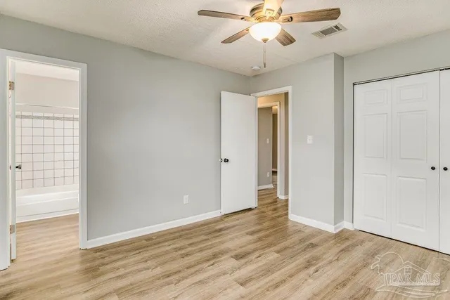 an empty room with wooden floor fan and windows