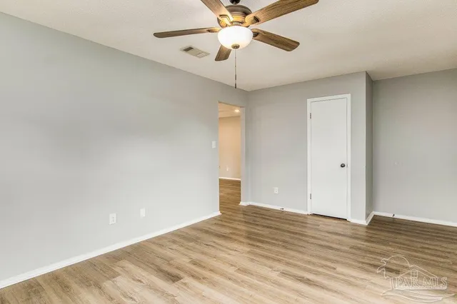a view of empty room with wooden floor and fan
