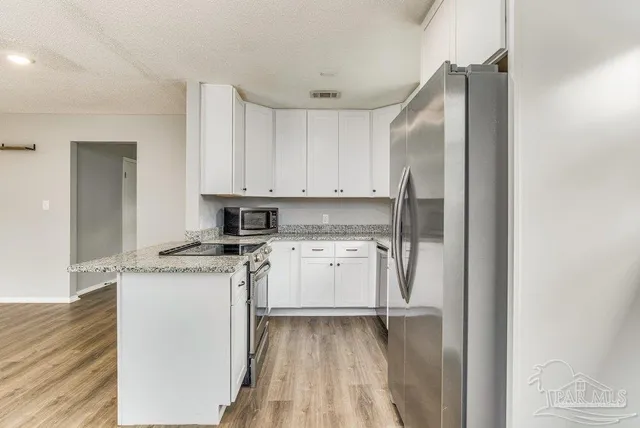 a kitchen with stainless steel appliances granite countertop a refrigerator and a stove top oven